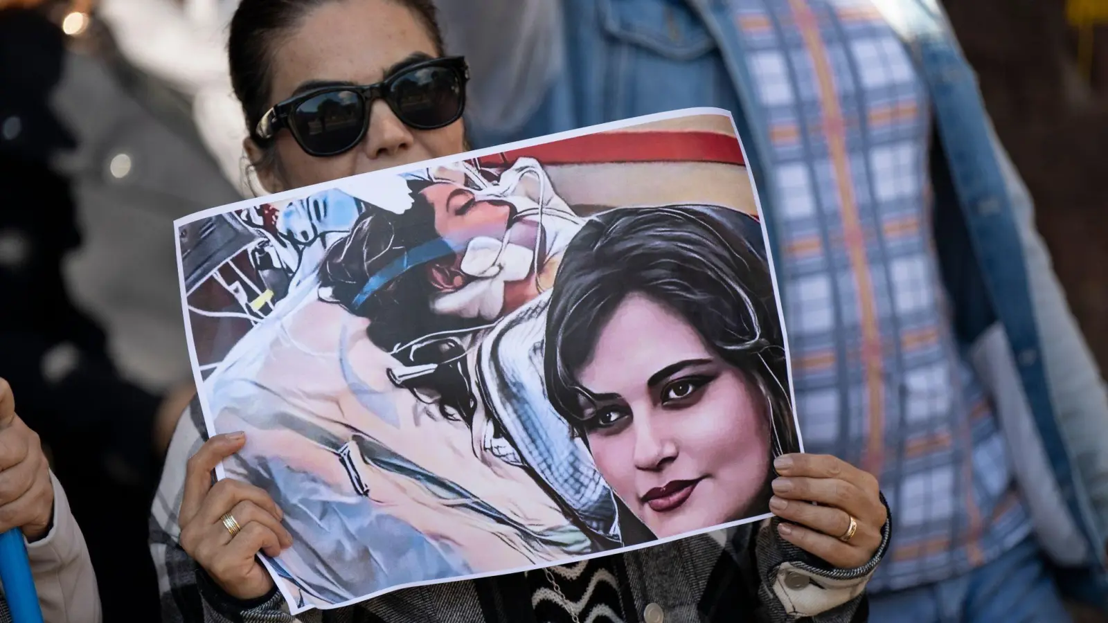 Eine Iranerin beteiligt sich in Frankfurt an einer Demonstration gegen das politische Regime im Iran. Dabei hält sie ein Plakat mit dem Bild der 22-jährigen  Mahsa Amini in den Händen. (Foto: Boris Roessler/dpa)