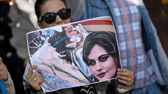 Eine Iranerin beteiligt sich in Frankfurt an einer Demonstration gegen das politische Regime im Iran. Dabei hält sie ein Plakat mit dem Bild der 22-jährigen  Mahsa Amini in den Händen. (Foto: Boris Roessler/dpa)