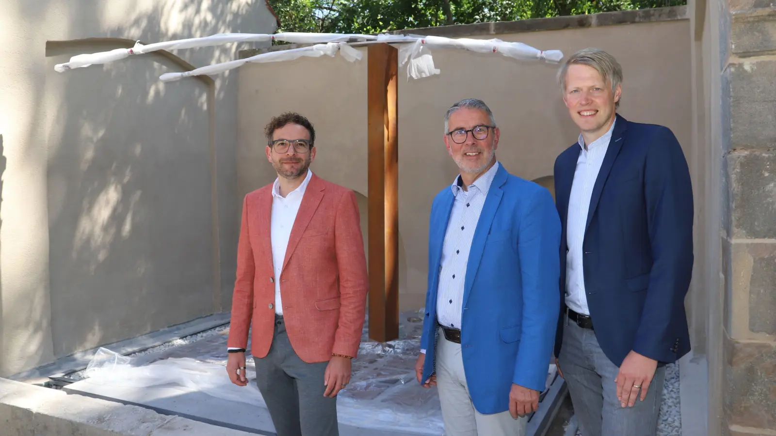 Meide Büdels Kunstwerk ziert die ehemalige Sturm-Gruft auf dem Friedhof. Darauf weisen Dekan Dr. Matthias Büttner (Mitte) sowie Frank Weihermann (links) und Manuel Dornhöfer von der Verwaltung hin. (Foto: Oliver Herbst)