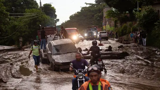 Menschen und Fahrzeuge stecken im Schlamm der durch Überschwemmungen und Erdrutsche auf die Straßen kam. Heftige Regenfälle in Venezuela führten zu Hochwasser in der Stadt Maracay im Bundesstaat Aragua. Es gab mehrere Todesopfer. (Foto: Juan Carlos Hernandez/ZUMA Press Wire/dpa)
