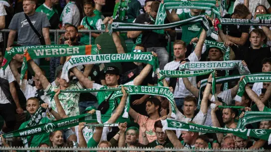 Fans von Werder Bremen stehen mit ihren Schals auf der Tribüne. (Foto: Swen Pförtner/dpa)
