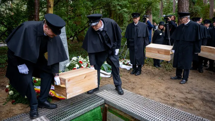 Die Gebeinekisten mit menschlichen Knochen werden nach der Trauerfeier in ein Grab auf dem Waldfriedhof Berlin-Dahlem hinabgelassen. (Foto: Monika Skolimowska/dpa)