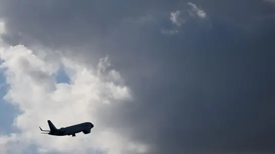 Ein Flugzeug fliegt nach seinem Sart am Flughafen München auf dunkle Wolke zu. (Foto: Angelika Warmuth/dpa)