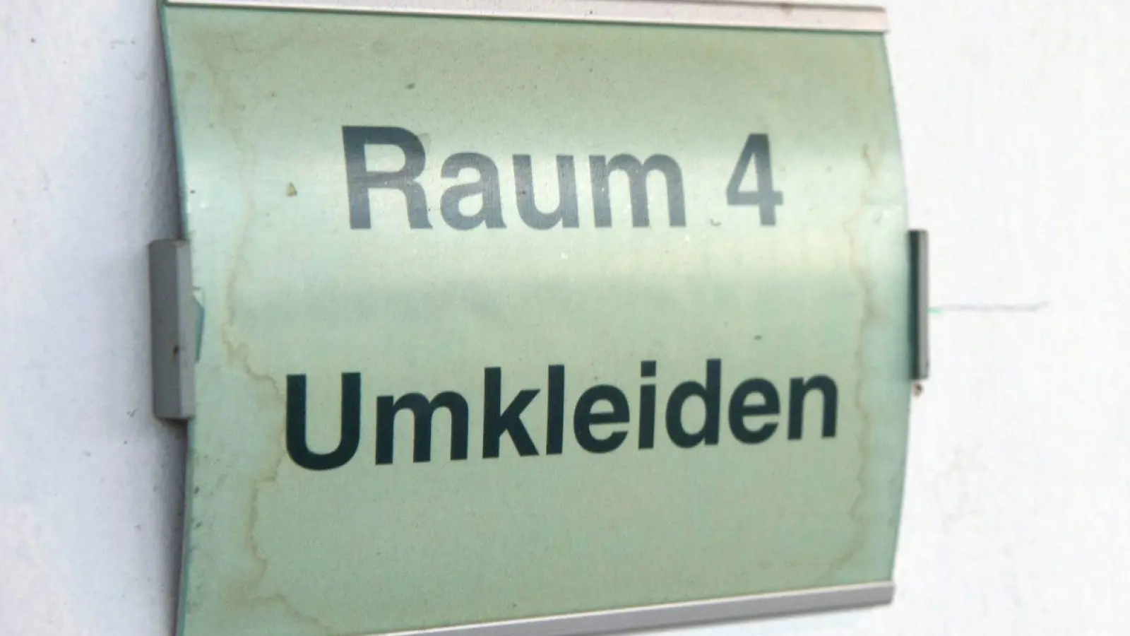 „Raum 4 - Umkleiden“ steht auf einem Schild an einem Sportplatz. (Foto: Paul Zinken/dpa)