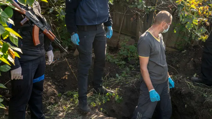 Beamte exhumieren die erste von zwei Leichen aus einem Grab als Teil einer Untersuchung von Kriegsverbrechen in dem ukrainischen Dorf Hrakowe. (Foto: David Ryder/ZUMA Press Wire/dpa)