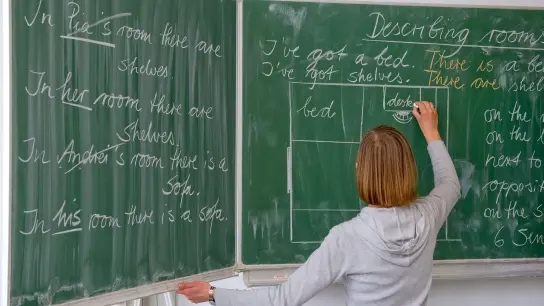 Eine Englisch-Lehrerin schreibt in einer Grundschule an die Tafel. (Foto: Patrick Pleul/dpa-Zentralbild/dpa)