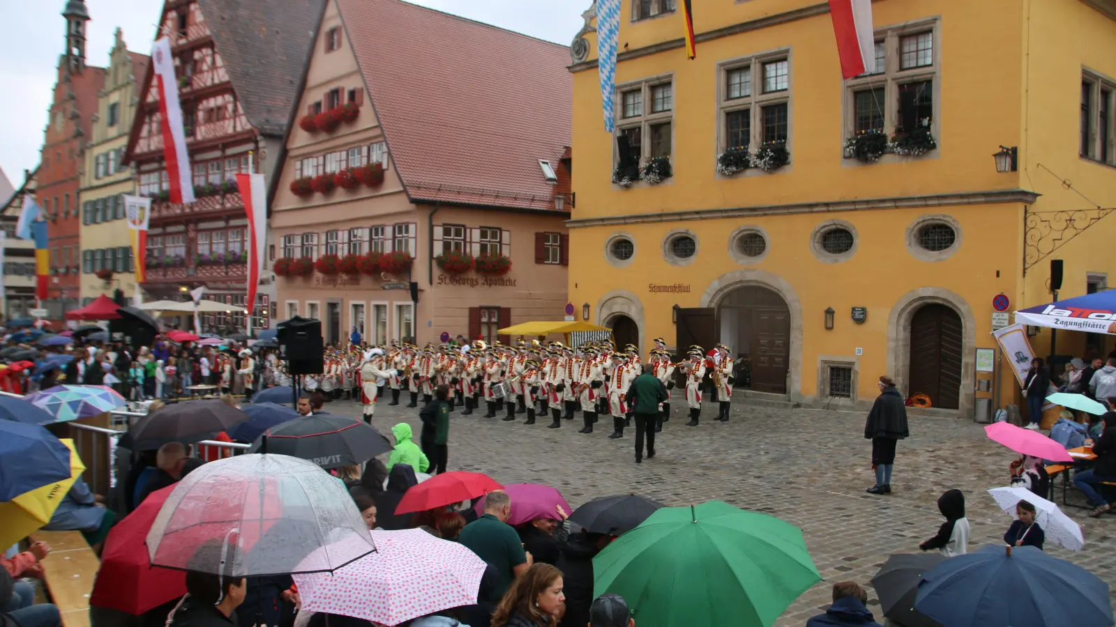 Unter Regenschirmen lauschte das Publikum dem kurzen Standkonzert der Knabenkapelle. (Foto: Martina Haas)