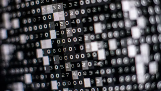 Eine fiktive Hackersoftware verschlüsselt in einer Maske auf dem Bildschirm Daten auf einer Festplatte. (Foto: Lino Mirgeler/dpa)