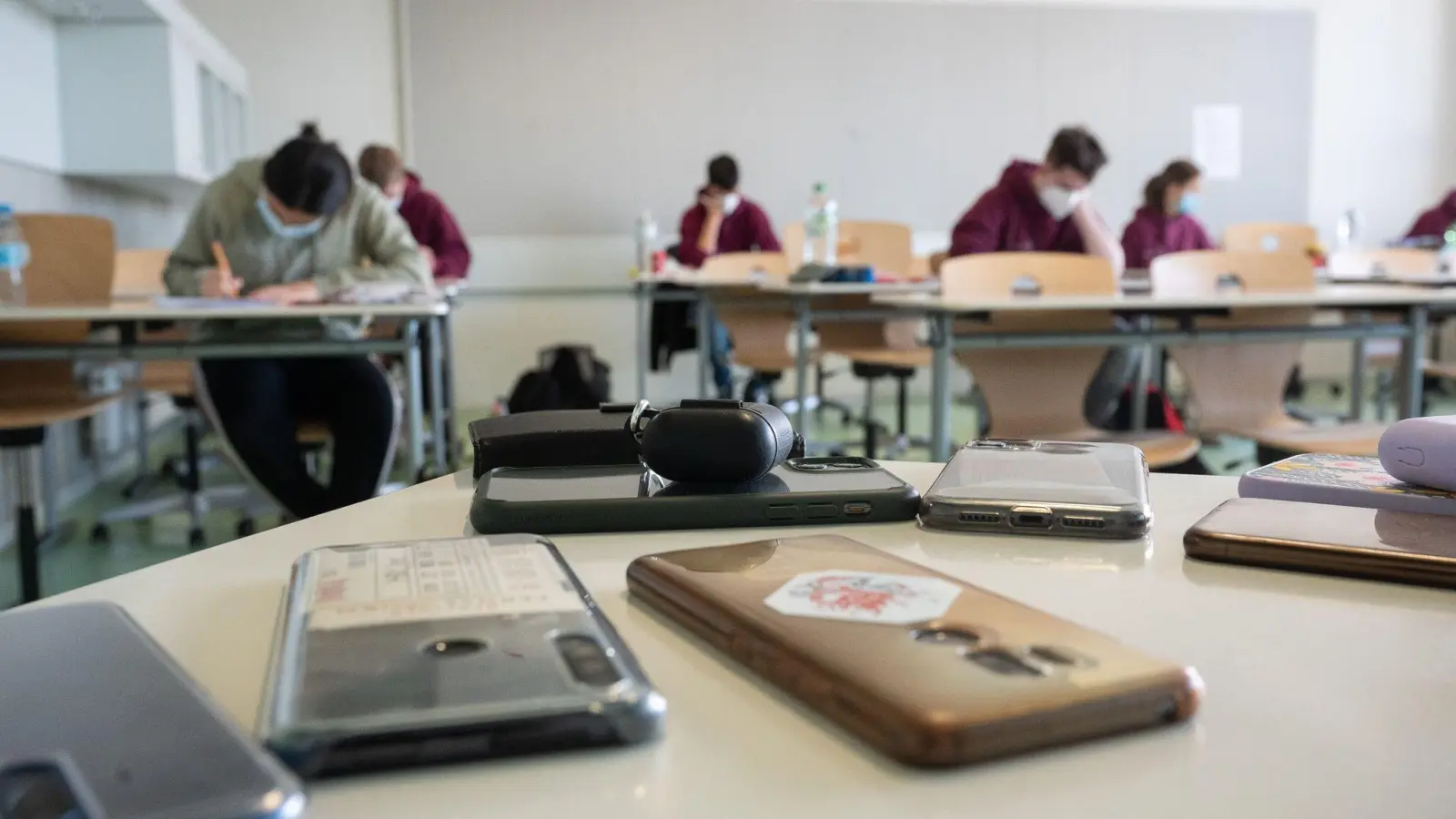 Ausgeschaltete Smartphones liegen am ersten Tag der Abiturprüfungen in einem Klassenzimmer. (Foto: Sebastian Gollnow/dpa/Archivbild)