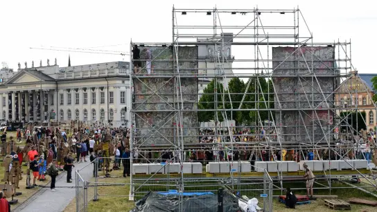Documenta-Mitarbeiter hängen das umstrittenene Großbanner „People&#39;s Justice“ des indonesischen Künstlerkollektivs Taring Padi auf dem Friedrichsplatz in Kassel gleich wieder ab. (Foto: Uwe Zucchi/dpa)
