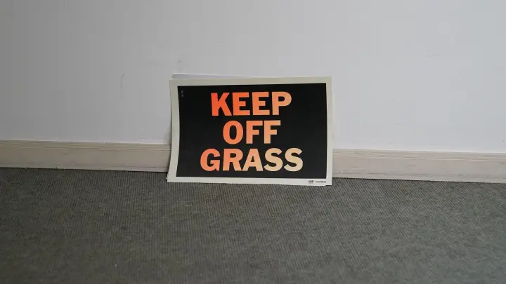 „Keep off Grass“ steht auf einem Zettel im Treppenhaus im Günter-Grass-Haus. Das Grass-Haus hat die handgeschriebenen Manuskripte zu „Grimms Wörtern“ von Literaturnobelpreisträger Günter Grass erworben. (Foto: Marcus Brandt/dpa)