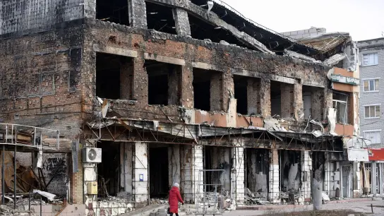Eine Frau geht an einem durch russischen Beschuss zerstörten Gebäude in der Region Charkiw vorbei. (Foto: -/Ukrinform/dpa/Symbolbild)