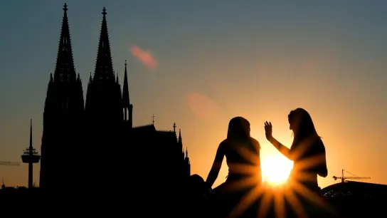 Zwei Frauen vor dem Kölner Dom:  Beim ersten Date verzichten junge Leute nach Tinder-Angaben heutzutage lieber auf Alkohol und treffen sich zu kulturellen Aktivitäten oder draußen statt im Restaurant. (Foto: Oliver Berg/dpa)