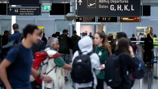 Passagiere stehen mit ihrem Gepäck vor der Sicherheitskontrolle am Flughafen München. (Foto: Sven Hoppe/dpa)