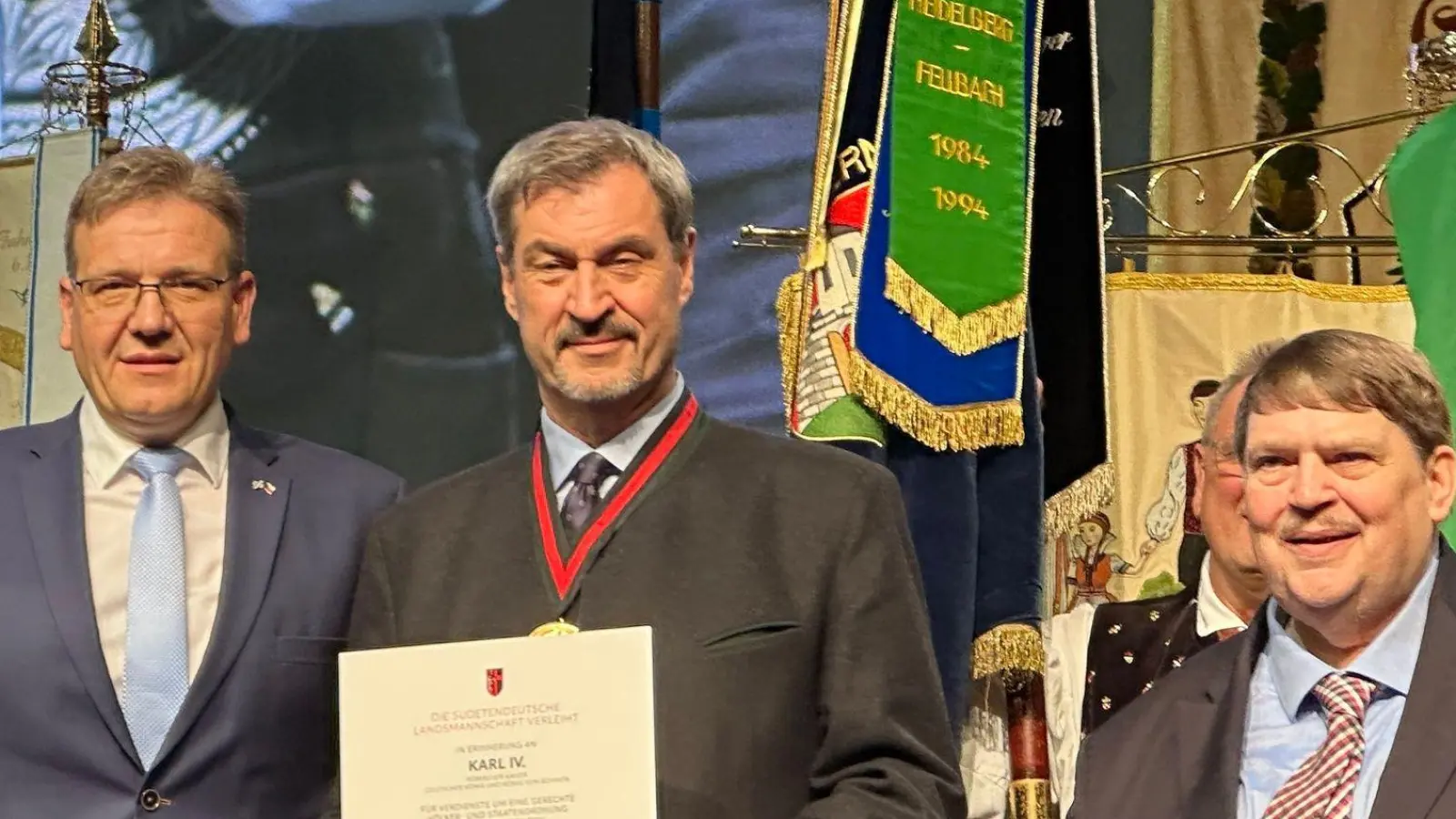 Ministerpräsident Markus Söder (CSU, M) freut sich über den Europäischen Karls-Preis der Sudetendeutschen Landsmannschaft. Überreicht haben die Auszeichnung Steffen Hörtler (l), Landesobmann der Sudetendeutschen Landsmannschaft, und Sprecher und Laudator Bernd Posselt. (Foto: Ute Wessels/dpa)