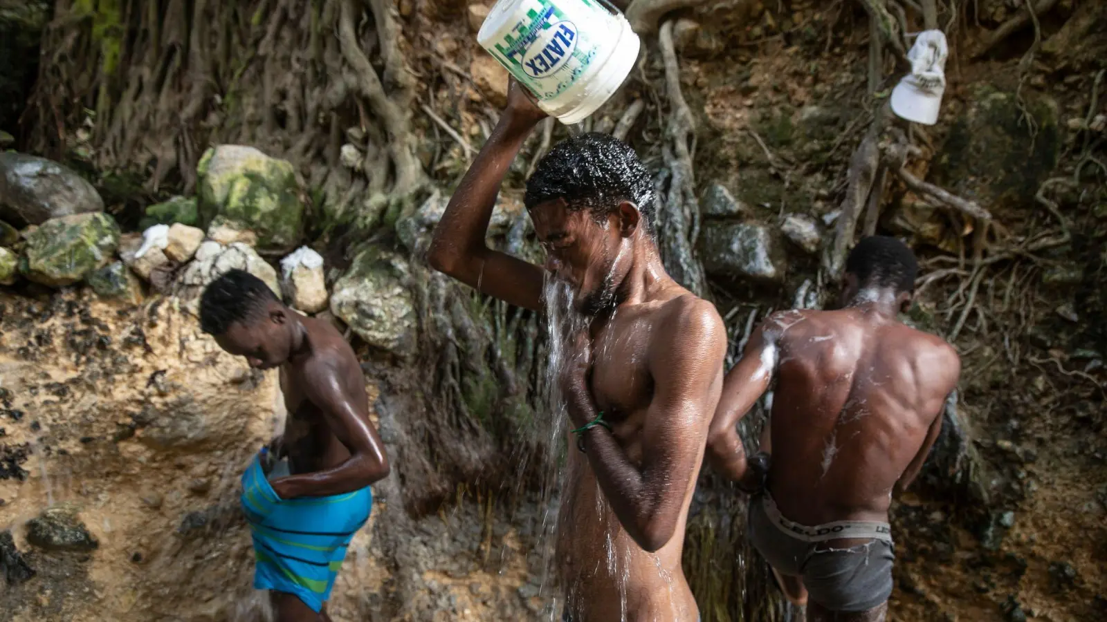 Menschen waschen sich in einer Schlucht in Port-Au-Prince. (Foto: Odelyn Joseph/AP/dpa)