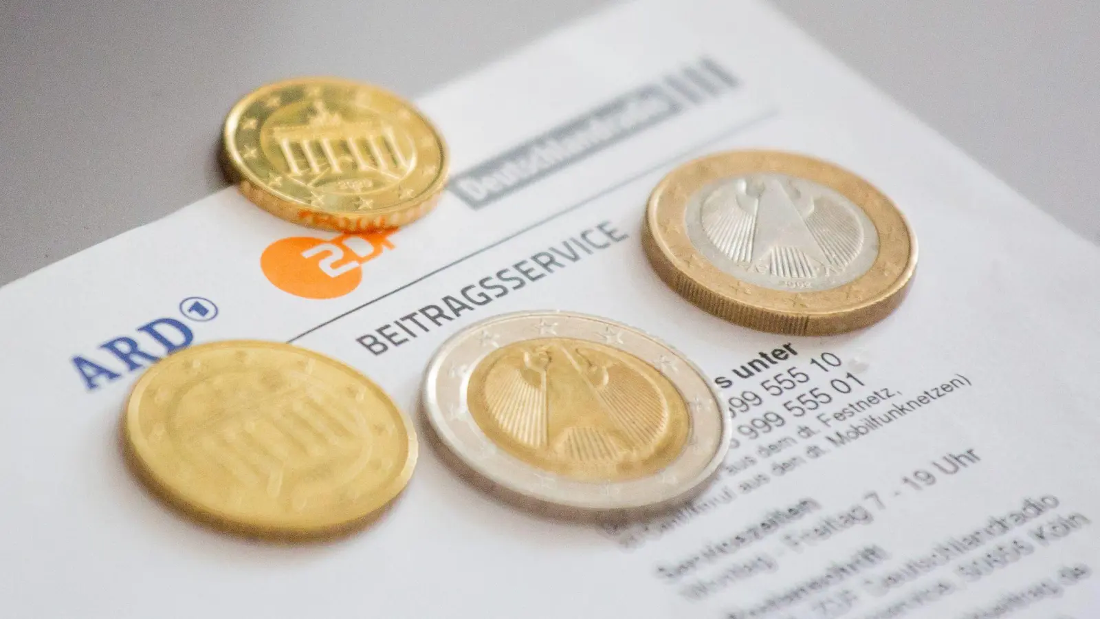 Euromünzen liegen auf einem Anschreiben zur Anmeldung für die Rundfunkgebühren. (Foto: Fernando Gutierrez-Juarez/dpa-Zentralbild/dpa/Illustration)