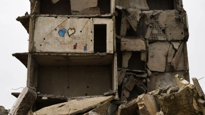 Ein zerstörtes Gebäude in Kramatorsk und zwei Herzen in den Farben der ukrainischen Flagge. (Foto: Andriy Andriyenko/AP/dpa)