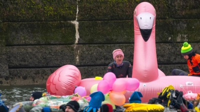 Teils bunt kostümiert schwimmen in und auf der eiskalten Donau Rettungsschwimmer.  (Foto: Stefan Puchner/dpa)