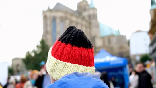 Ein Besucher des Bürgerfestes zum Tag der Deutschen Einheit trägt auf dem Domplatz eine schwarz-rot-goldene Mütze. (Foto: Sebastian Willnow/dpa)