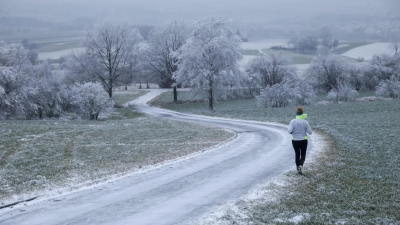Joggerin trotzt Schnee und Raureif an Heiligabend in Uttenweiler (Foto: Thomas Warnack/dpa)
