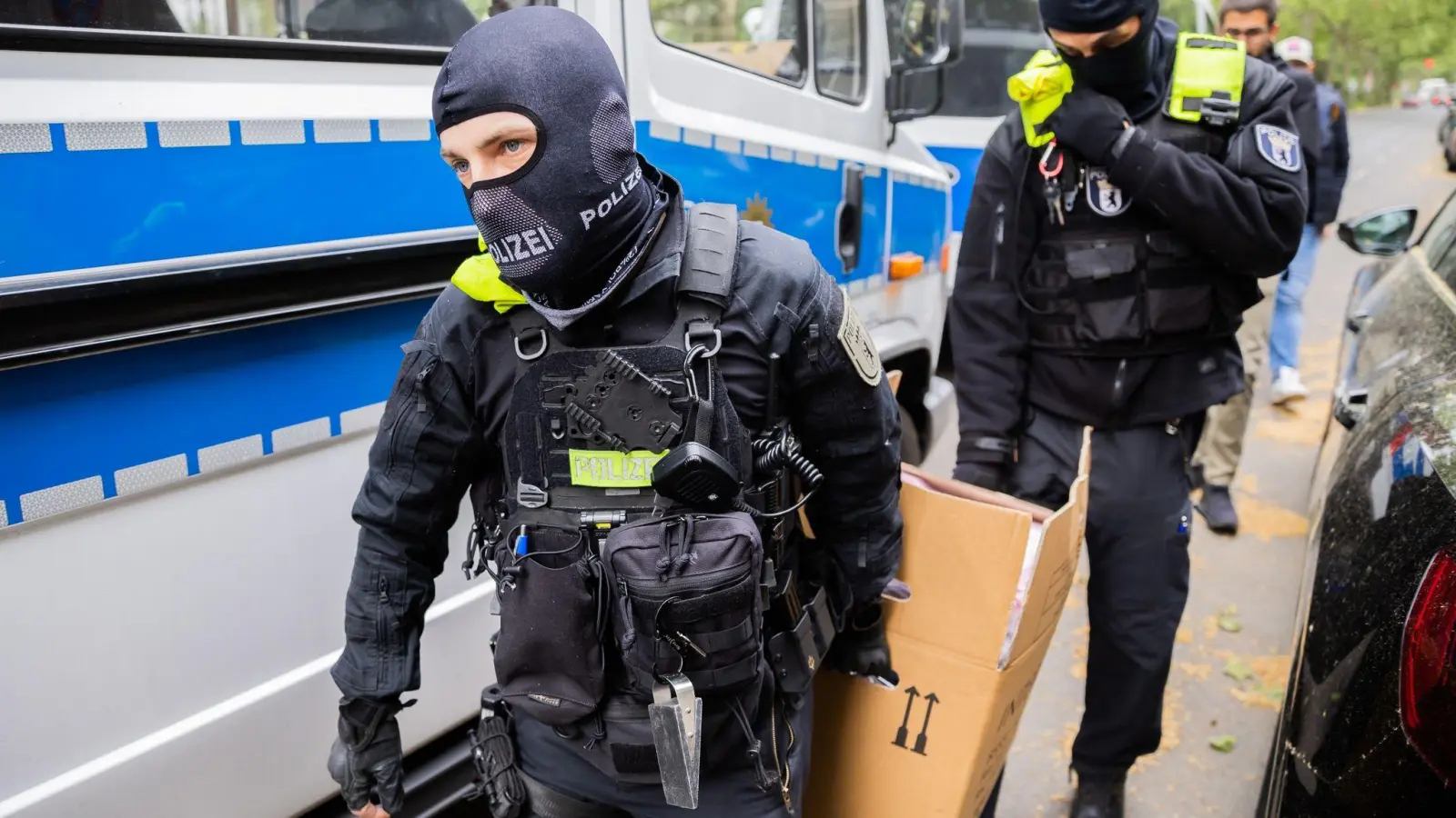 Polizisten tragen bei einer Hausdurchsuchung in Berlin-Kreuzberg einen Karton zu einem Fahrzeug. (Foto: Christoph Soeder/dpa)