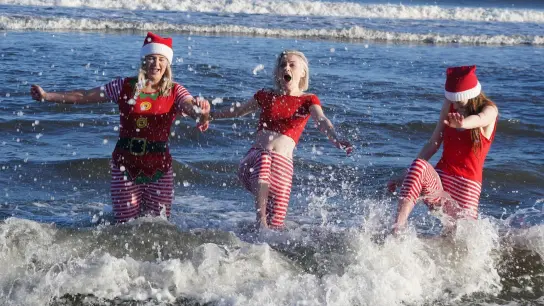 Eine Gruppe junger Frauen in Weihnachtskostümen planscht während des jährlichen Weihnachtsschwimmens am Long Sands Beach. (Foto: Owen Humphreys/PA Wire/dpa)