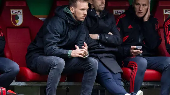 Bayerns Trainer Julian Nagelsmann (l) sitzt während der Partie beim FC Augsburg auf der Trainerbank. (Foto: Tom Weller/dpa)