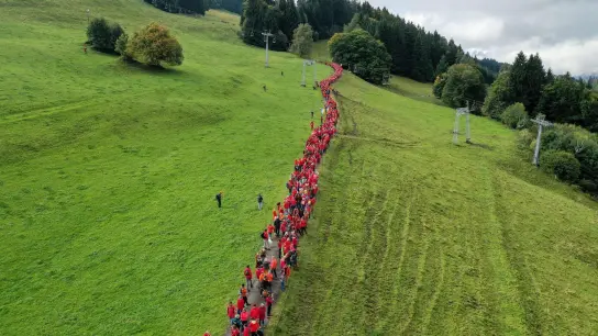 Gegner des Seilbahnprojekts am Grünten im Allgäu bilden eine Menschenkette am alten Grüntenlift (Luftaufnahme mit einer Drohne). (Foto: Karl-Josef Hildenbrand/dpa)