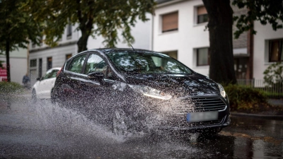 Nach starken Regenfällen am Dienstagmorgen fährt ein Auto durch eine große Pfütze in Duisburg. (Foto: Christoph Reichwein/dpa)