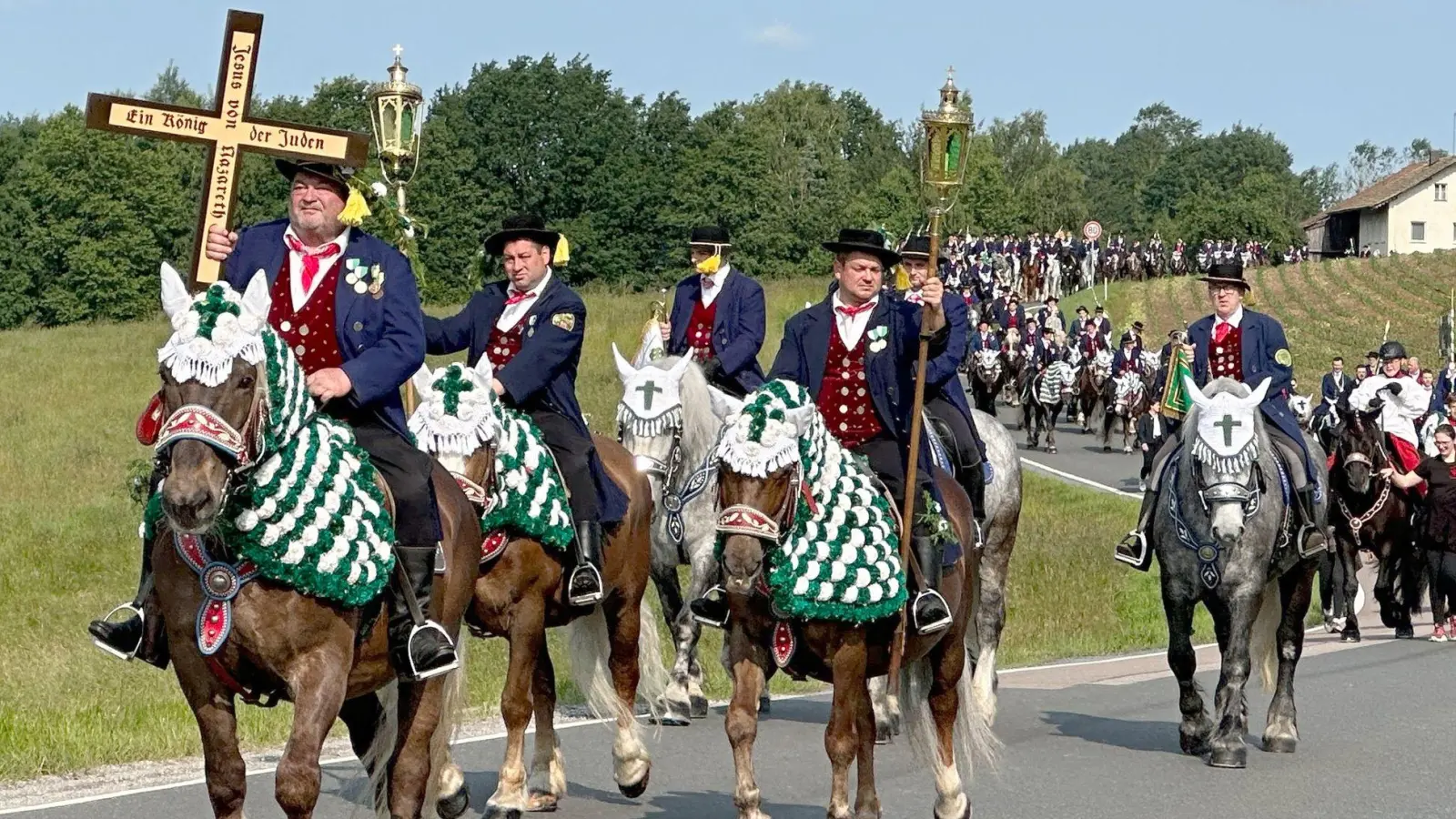 Auf geschmückten Pferden sind die Reiter beim Kötztinger Pfingstritt unterwegs. (Foto: Ute Wessels/dpa)