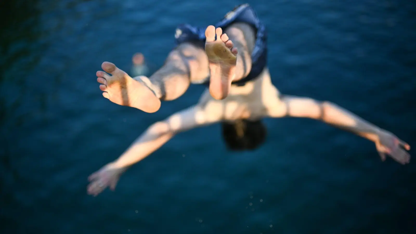 Sprung ins kühle Nass: Ein Mann springt bei Hitze in Zürich von einer Brücke in den Fluss Limmat. (Foto: Sebastian Christoph Gollnow/dpa)
