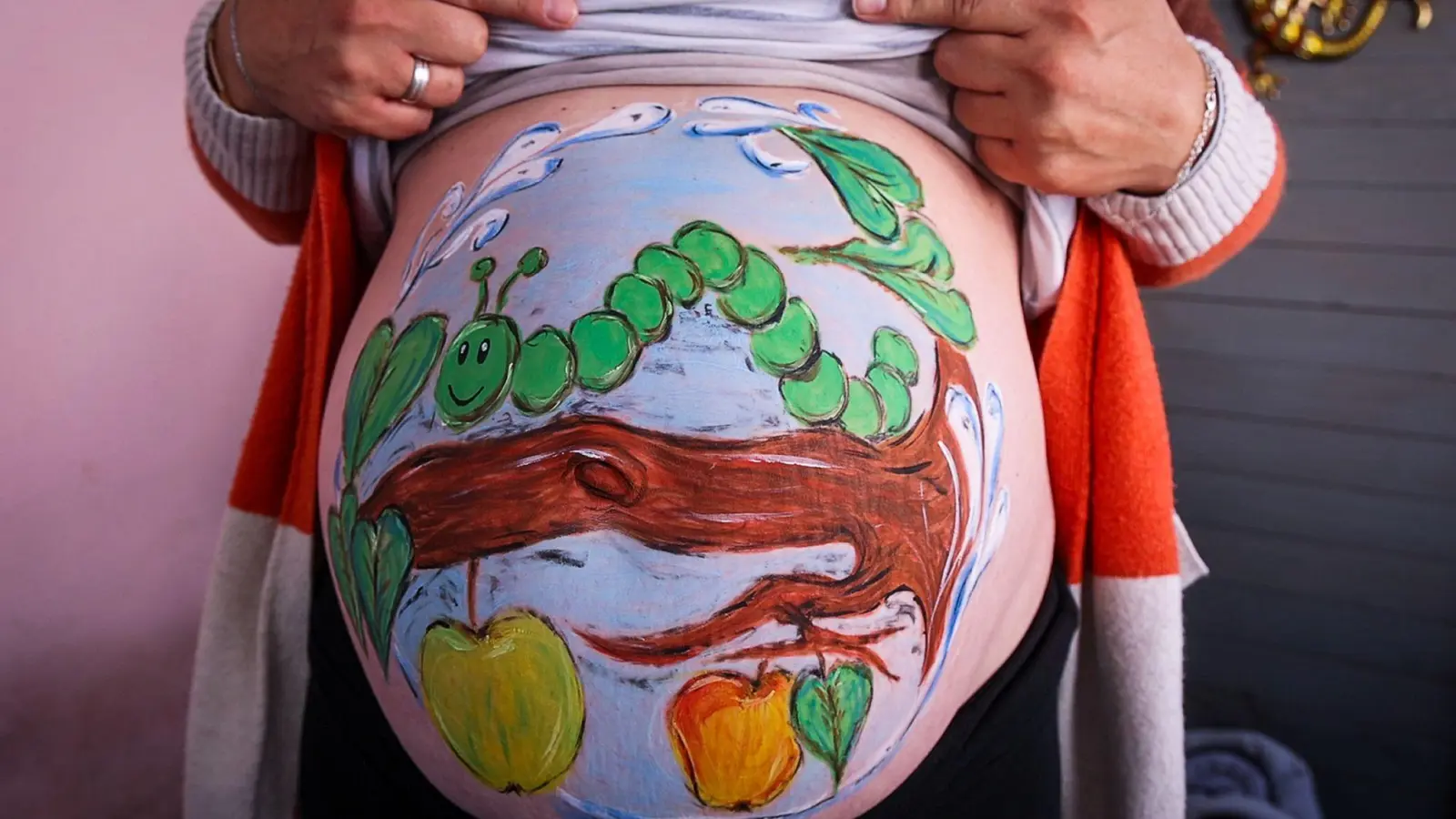 Die Hobbymalerin Marienn Pyko hat der Schwangeren Sandra Genz eine kleine hungrige Raupe auf den Babybauch gemalt. (Foto: Jens Büttner/dpa)