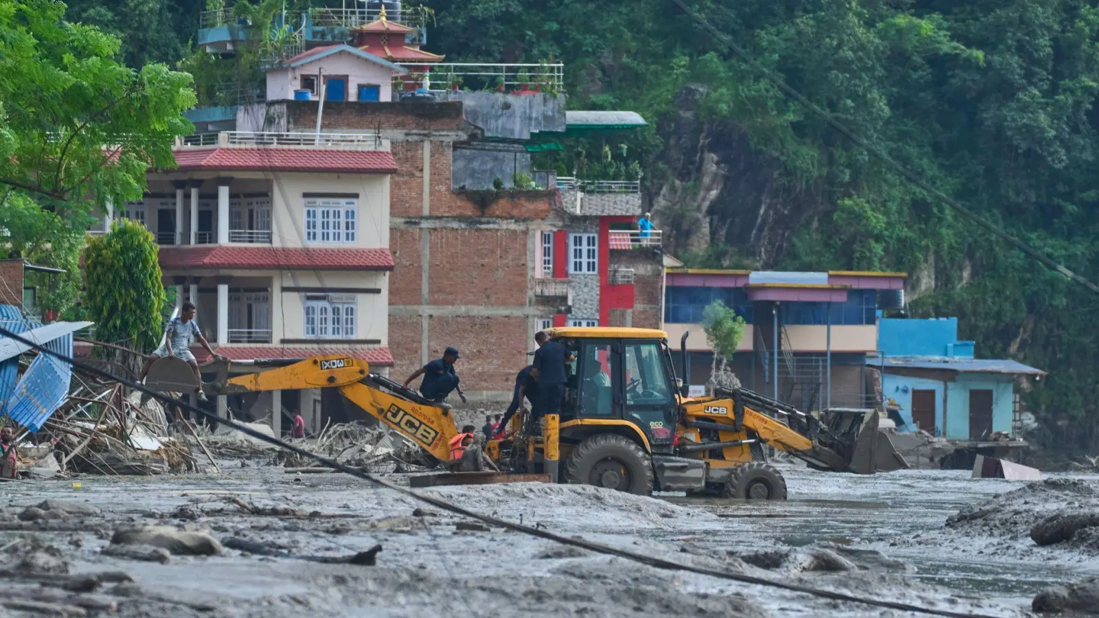 Rettungskräfte setzen Baumaschinen ein, um unter Wasser stehende Häuser nach Sturzfluten zu erreichen. (Foto: Niranjan Shrestha/AP/dpa)