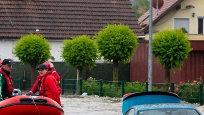 Die Wasserwacht fährt mit einem Schlauchboot durch eine überflutete Straße. (Foto: Stefan Puchner/dpa)