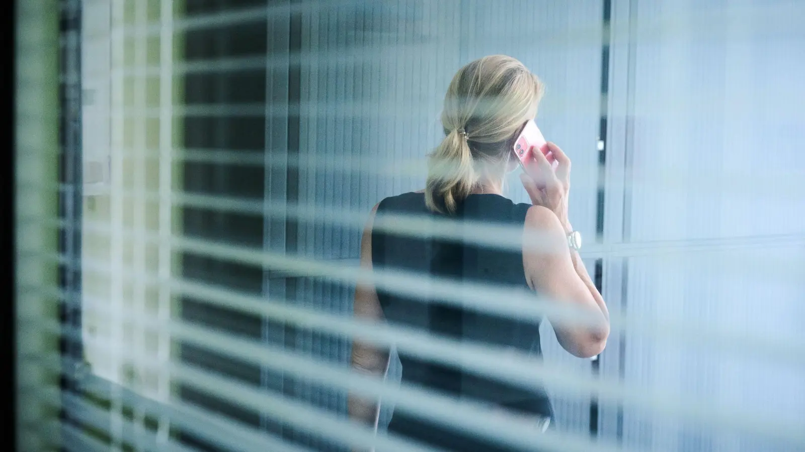 Eine Frau steht in einem Büro und telefoniert. (Foto: Annette Riedl/dpa/Illustration)