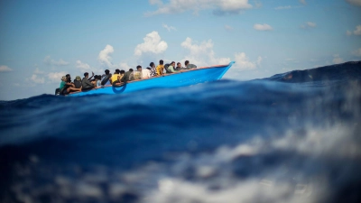 Migranten sitzen in einem Holzboot südlich der italienischen Insel Lampedusa auf dem Mittelmeer. (Foto: Francisco Seco/AP/dpa)