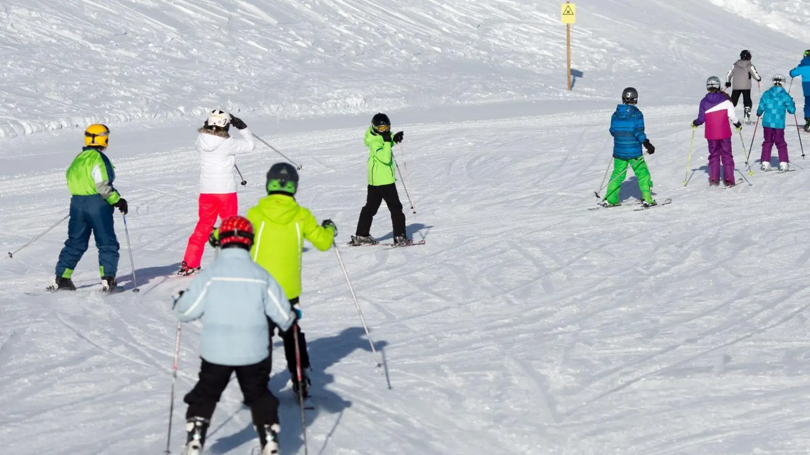 Bekanntes Bild aus den Skigebieten: Skischüler fahren in Reih und Glied die Piste ab. (Foto: Florian Schuh/dpa-tmn)