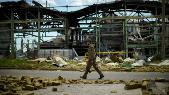 Ein ukrainischer Soldat geht an einer durch Beschuss zerstörten Fabrik vorbei. (Foto: Francisco Seco/AP/dpa)