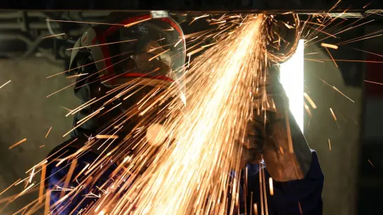 Ein Mitarbeiter eines Maschinenbauers schneidet mit einem Trennschleifer korrodierte Metallteile aus dem Träger in einem Wagenkasten. (Foto: Jan Woitas/dpa-Zentralbild/dpa)