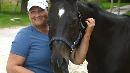 Trainerin Anke Dahlhaus umarmt ein Pferd. In anderen Ländern sind Umschulungsstätten für ehemalige Rennpferde gang und gebe - in Deutschland gibt es nur eine. (Foto: Sabine Maurer/dpa)