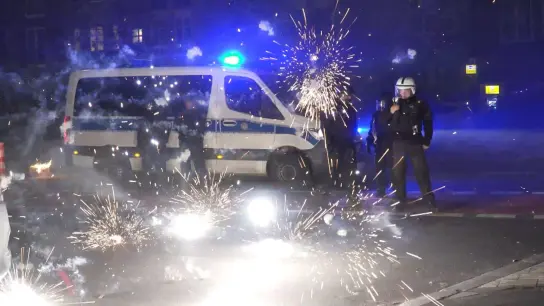 Polizeibeamte hinter explodierendem Feuerwerk in Berlin (Foto: Julius-Christian Schreiner/TNN/dpa)