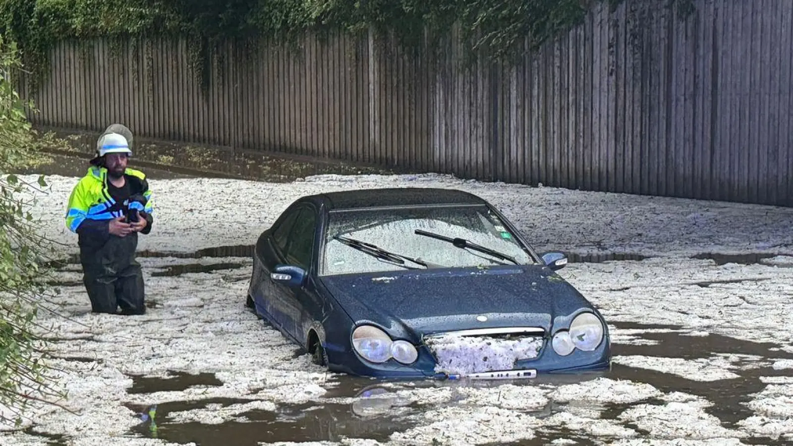 Nach schweren Unwettern steht ein Auto auf einer überfluteten Straße, in der Hagelkörner treiben. (zu dpa: «Sturm und Hagel: 1,3 Milliarden Unwetterschäden an Autos») (Foto: Michael Breher)