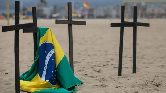 Eine brasilianische Fahne hängt an einem der Kreuze bei einer Gedenkveranstaltung für einen ungewöhnlichen Corona-Protest. Die Nichtregierungsorganisation Rio de Paz erinnert mit dieser Aktion an die Opfer. (Foto: Bruna Prado/AP/dpa)