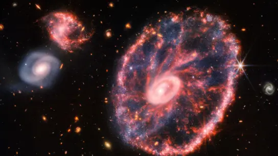 Dieses von der NASA zur Verfügung gestellte Handout-Foto zeigt eine große, rosa-blau gesprenkelte Galaxie, die einem Rad mit einem kleinen, inneren Oval ähnelt. (Foto: Uncredited/NASA/AP/dpa)