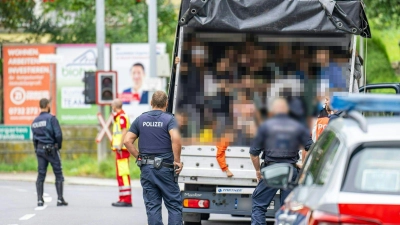 Polizisten stehen bei einer Kontrolle in Österreich an einem Kleintransporter. Die Beamten entdeckten dabei 53 Personen auf der Ladefläche. (Foto: Werner Kerschbaummayr/Fotokersch/APA/dpa)