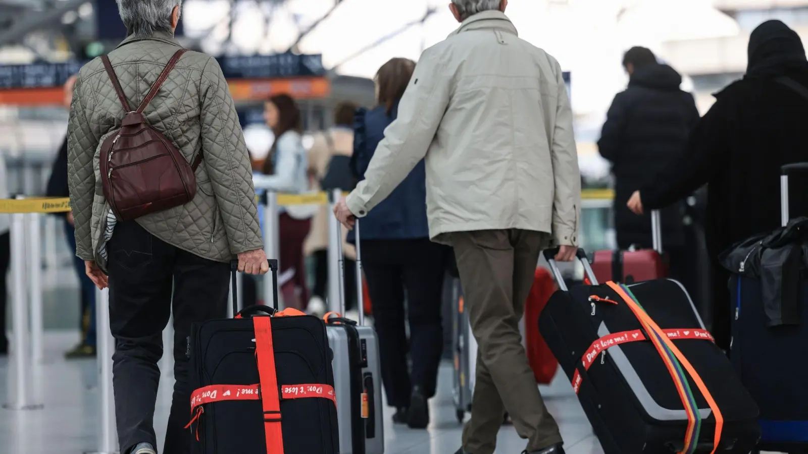 Ältere Reisende gehen am Flughafen mit Reisekoffern durch das Terminal. (Foto: Oliver Berg/dpa)