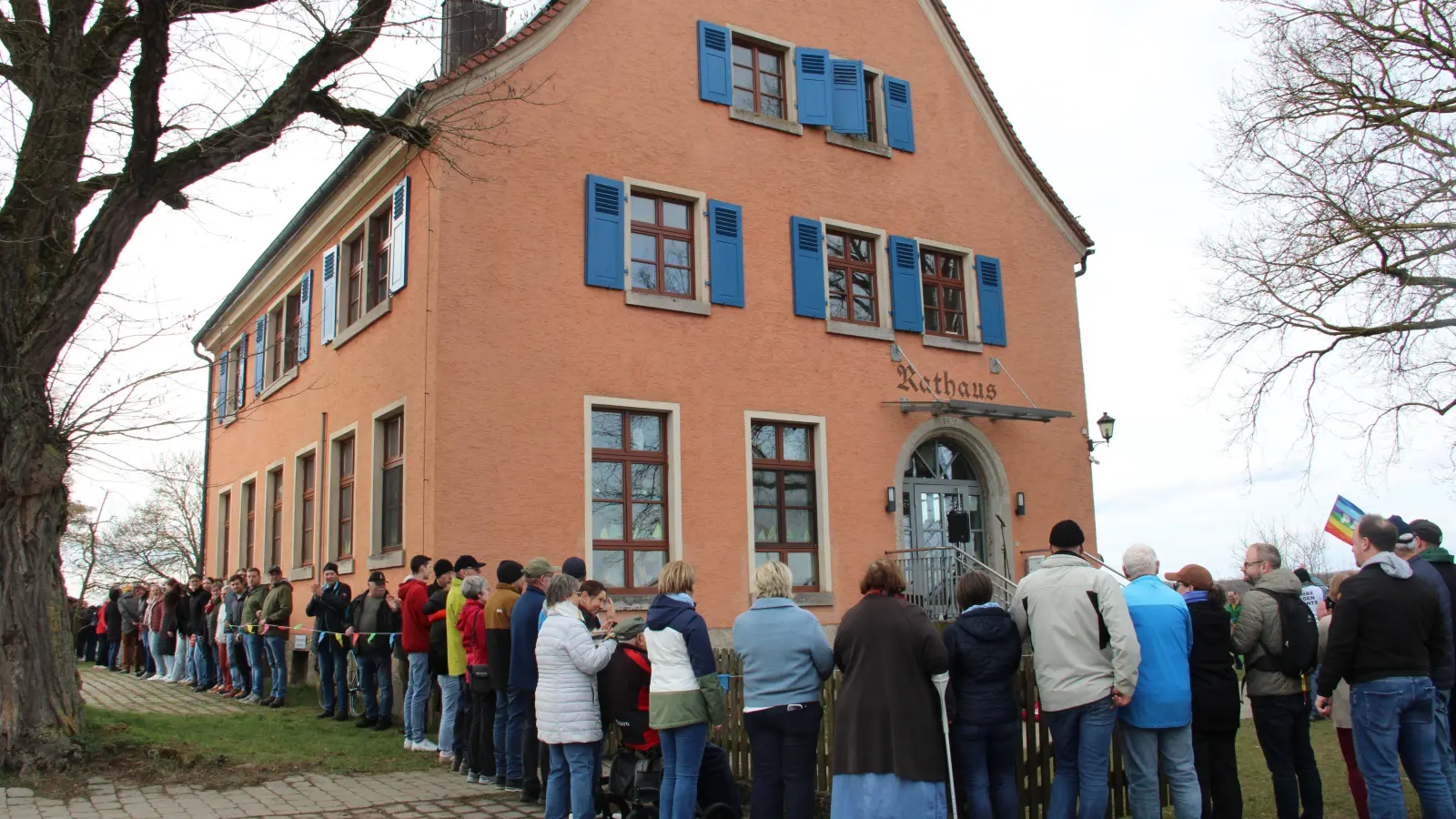 Geschätzt knapp 250 Menschen haben am Samstagnachmittag eine Menschenkette um das Rathaus in Adelshofen gebildet, um es symbolisch zu schützen. (Foto: Clarissa Kleinschrot)