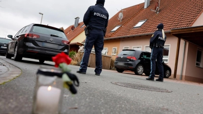 Polizisten stehen neben einer Trauerkerze vor einem Haus. Eine Gewalttat hat den 6800-Einwohner-Ort Weisendorf erschüttert.  (Foto: Daniel Löb)