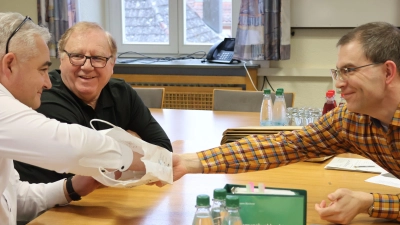 Bürgermeister Claus Seifert (links) zieht in seiner Funktion als Wahlausschussvorsitzender eines der Lose, die Georg Münich (rechts) vorbereitet und in eine Papiertüte geworfen hatte. Hans Müller, CSU-Vertreter im Wahlausschuss, beäugt den Vorgang. (Foto: Andreas Reum)